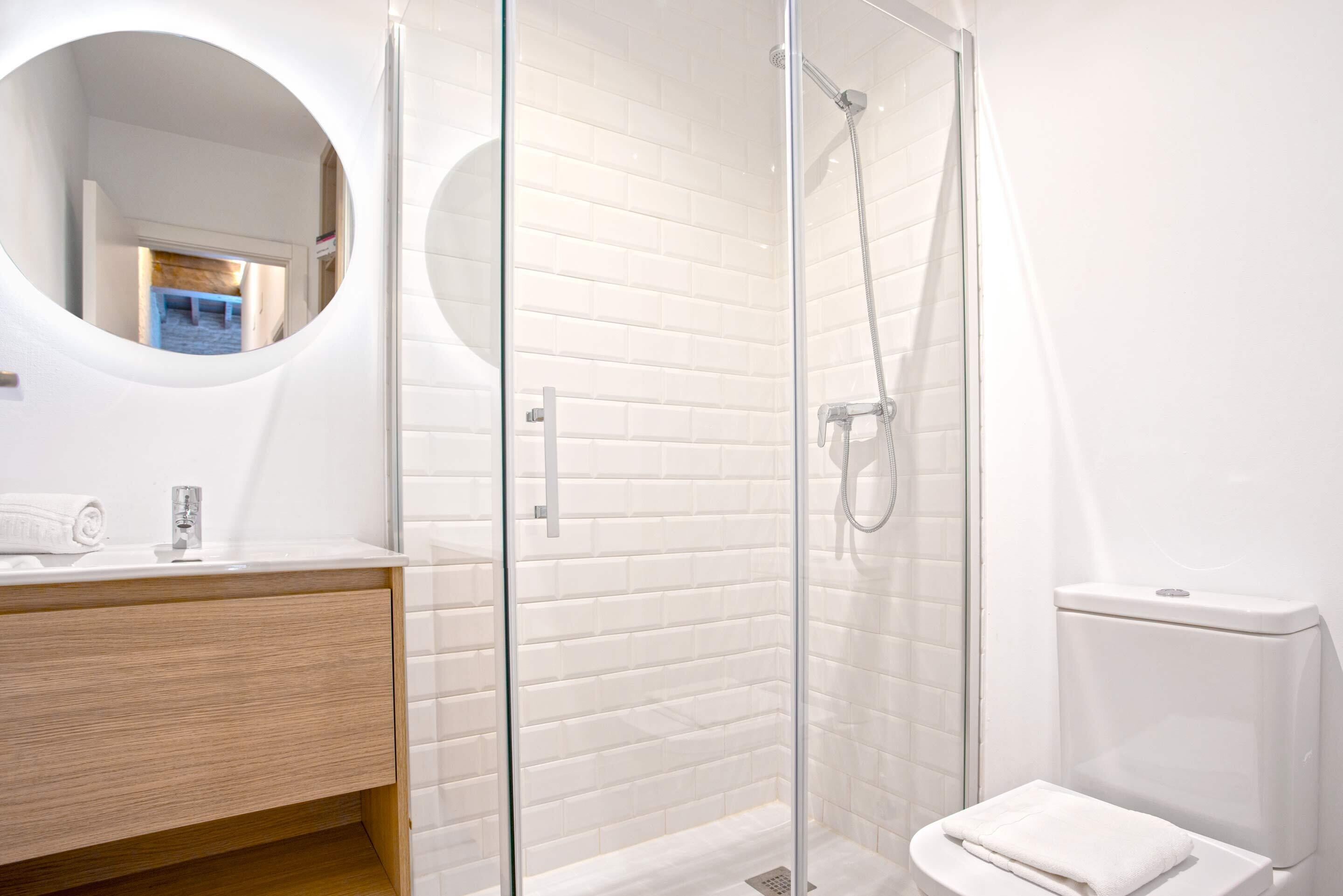 Une salle de bain moderne avec une douche à parois de verre, un meuble-lavabo en bois et des toilettes blanches.
