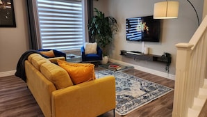 Un saló amb un sofà, una taula de centre, una televisió i una escala.