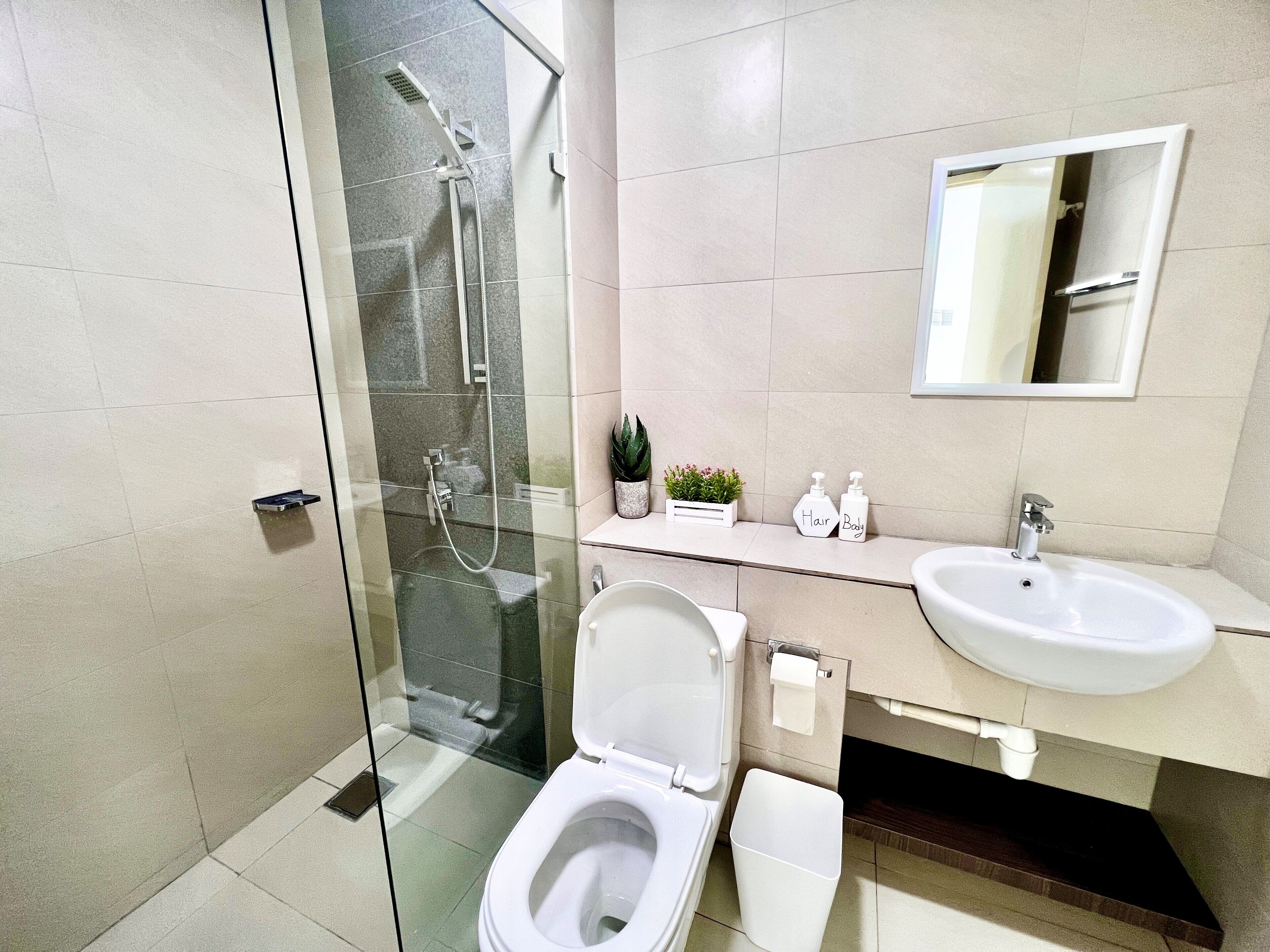 A modern bathroom with a glass-enclosed shower, a white toilet, a sink, and a mirror above the sink.