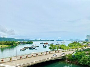 A bridge over a river with boats, greenery, and a distant mountain range. - Deco Home Imago The Loft (Kota Kinabalu)
