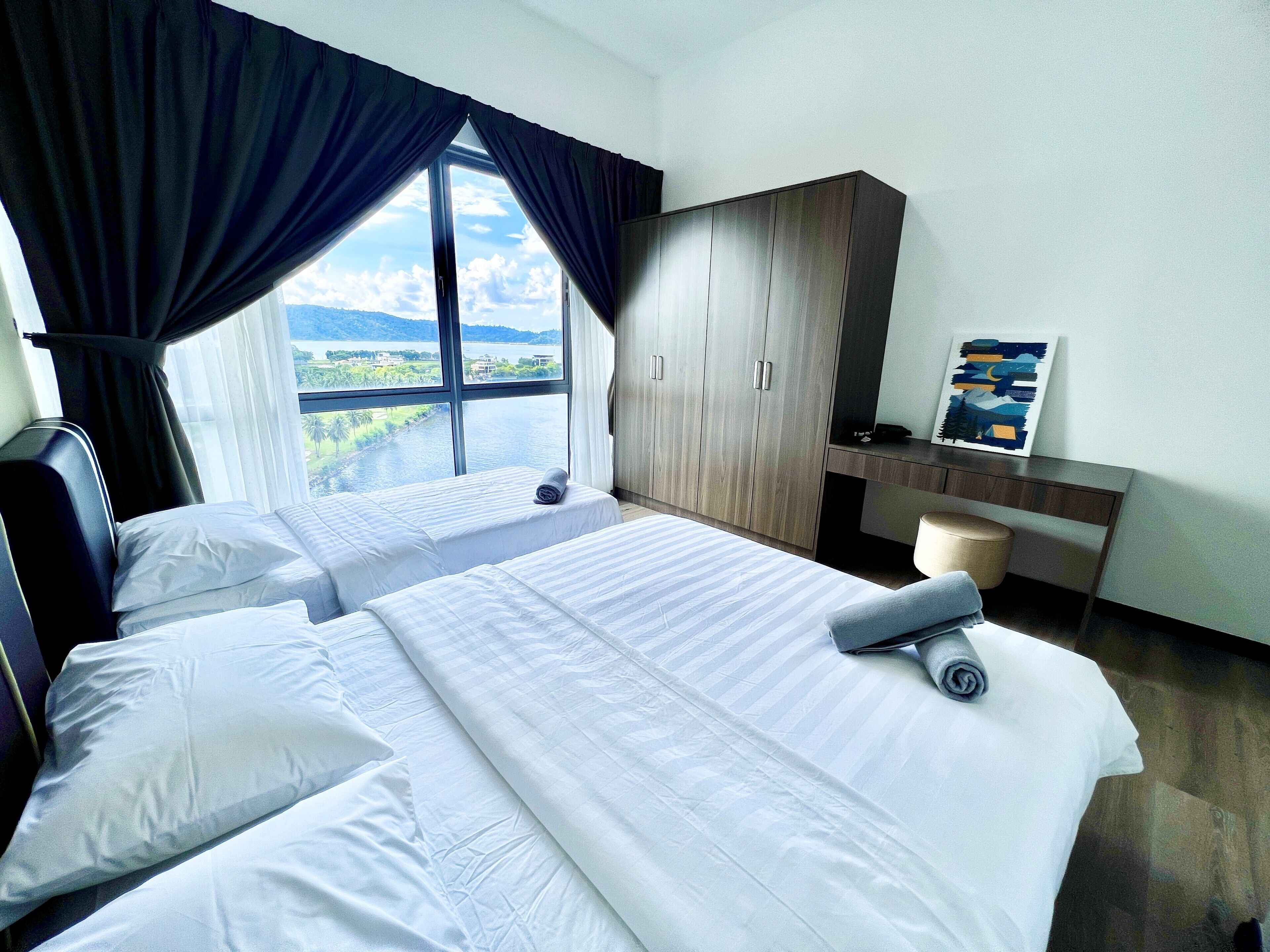 Una habitación de hotel con dos camas, un escritorio y un ventanal con cortinas.