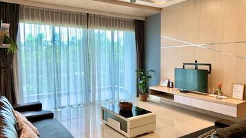 A modern living room with a sofa, coffee table, and TV on a wooden wall.