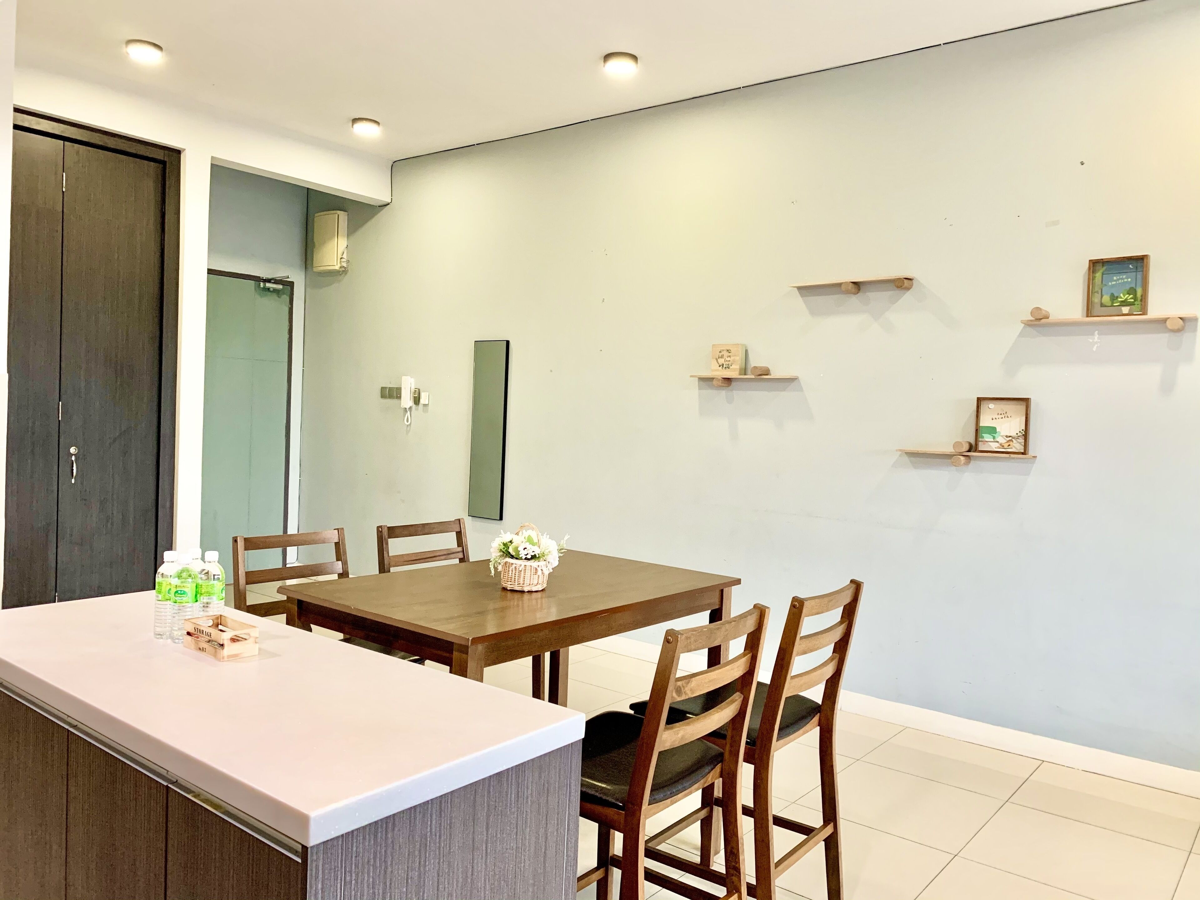 A dining area with a wooden table and chairs, a small island with a basket of flowers, and a wall-mounted phone.