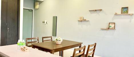 A dining area with a wooden table and chairs, a small island with a basket of flowers, and a wall-mounted phone.