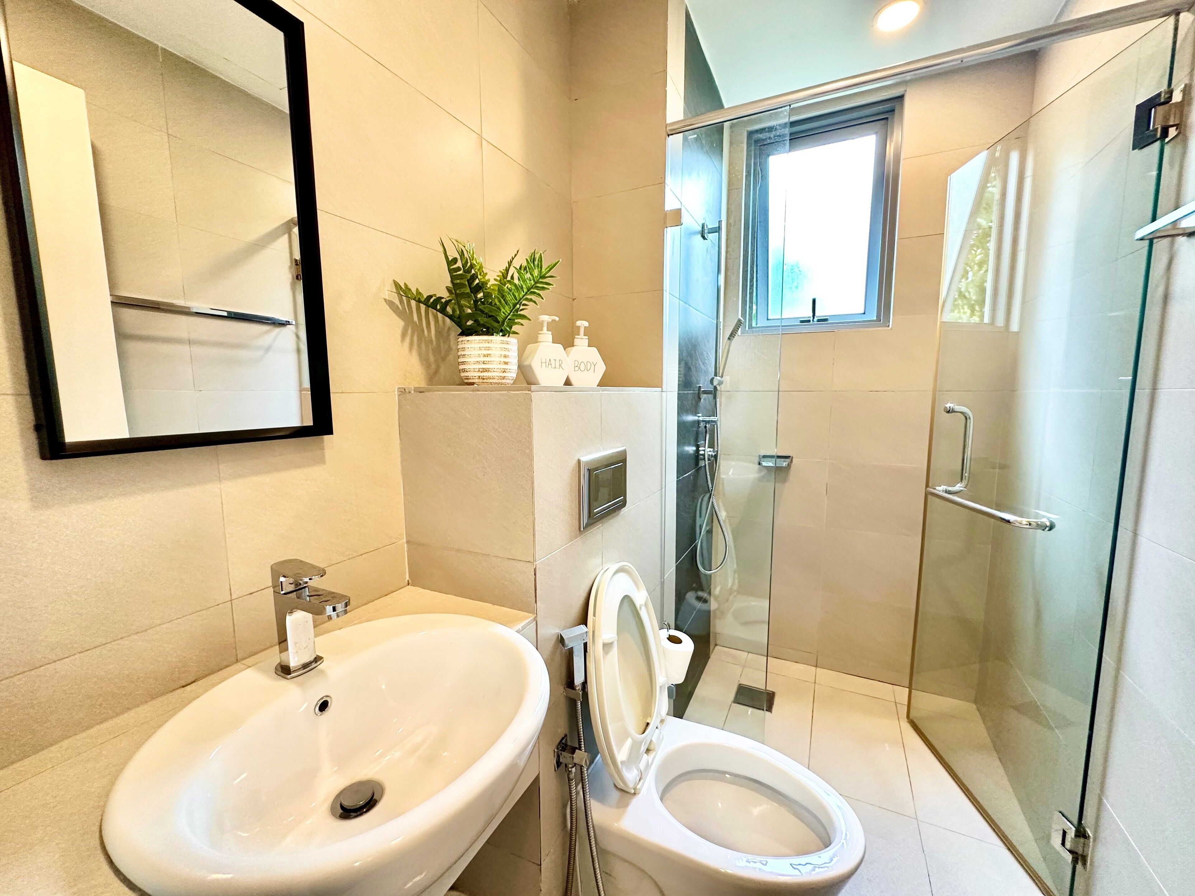 A modern bathroom with a white sink, toilet, and glass-enclosed shower.