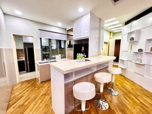 A modern kitchen with a central island, bar stools, and built-in appliances. - Deco Home Imago The Loft (Kota Kinabalu)