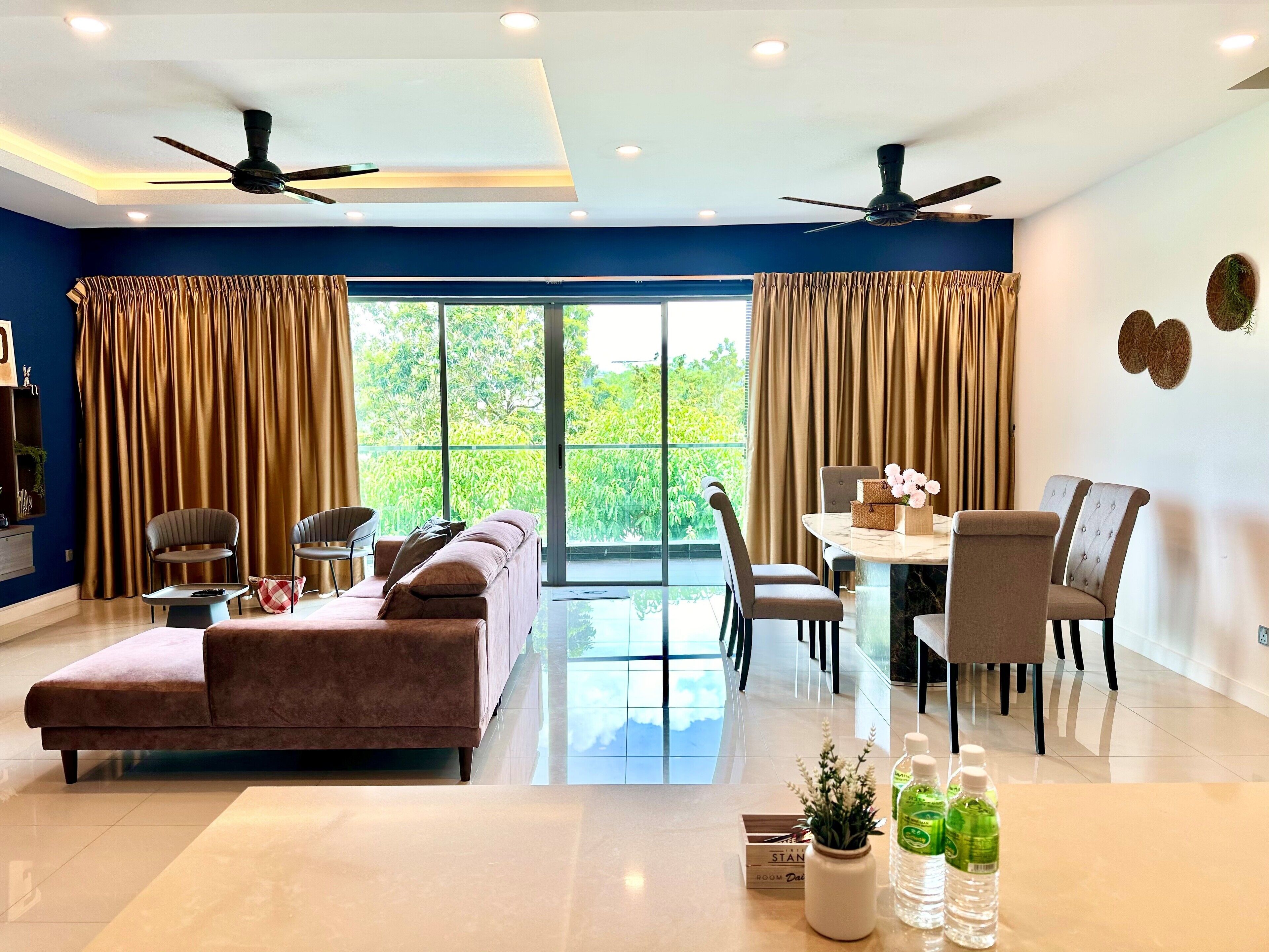 A spacious living room with a sofa, chairs, a dining table, and a balcony with curtains.