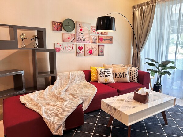 A living room with a red sofa, a white coffee table, and a large potted plant. - Deco Home Imago The Loft (Kota Kinabalu)