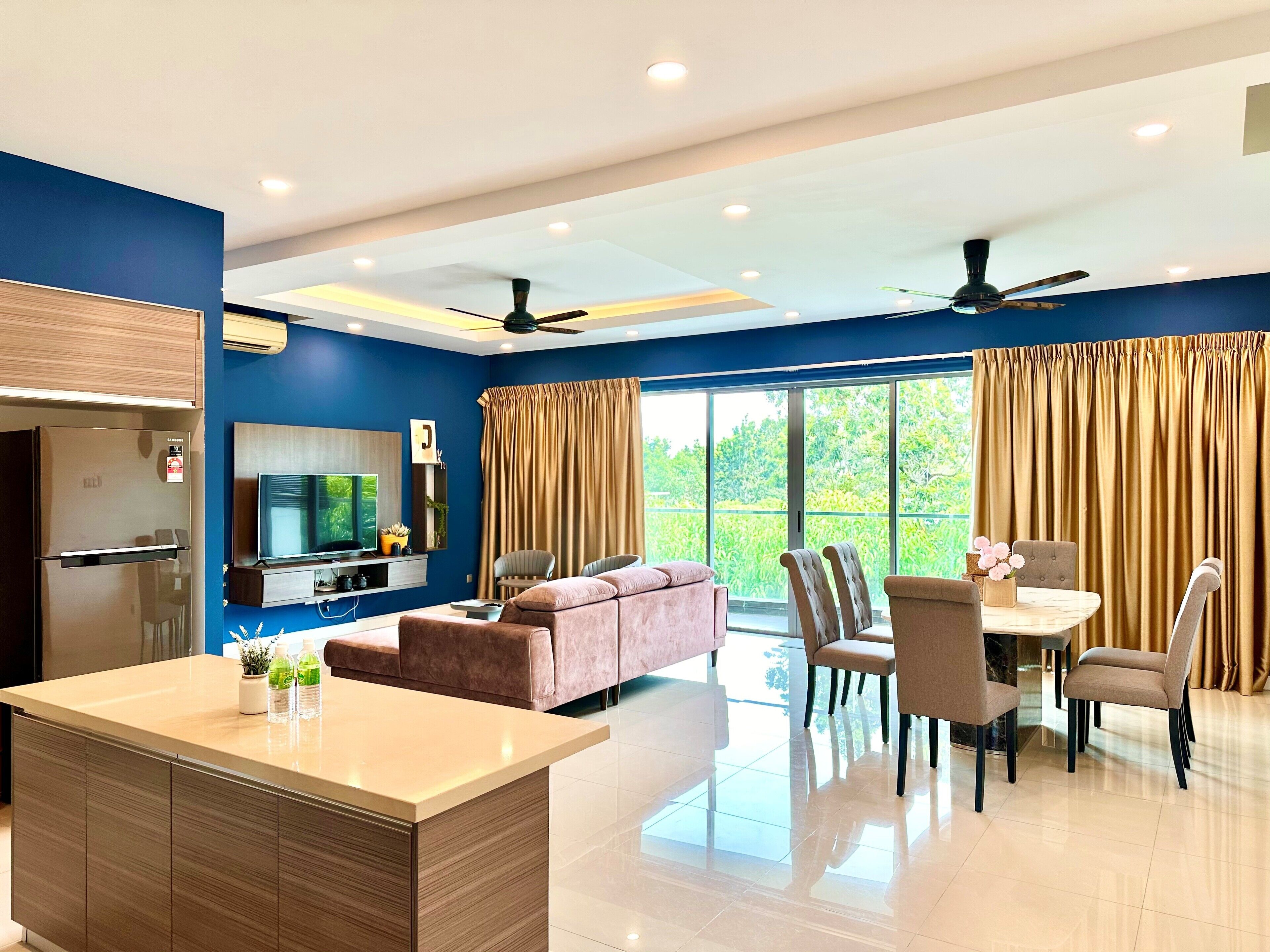 A modern living room with a kitchen area, a dining table with chairs, a sofa, and a ceiling fan.
