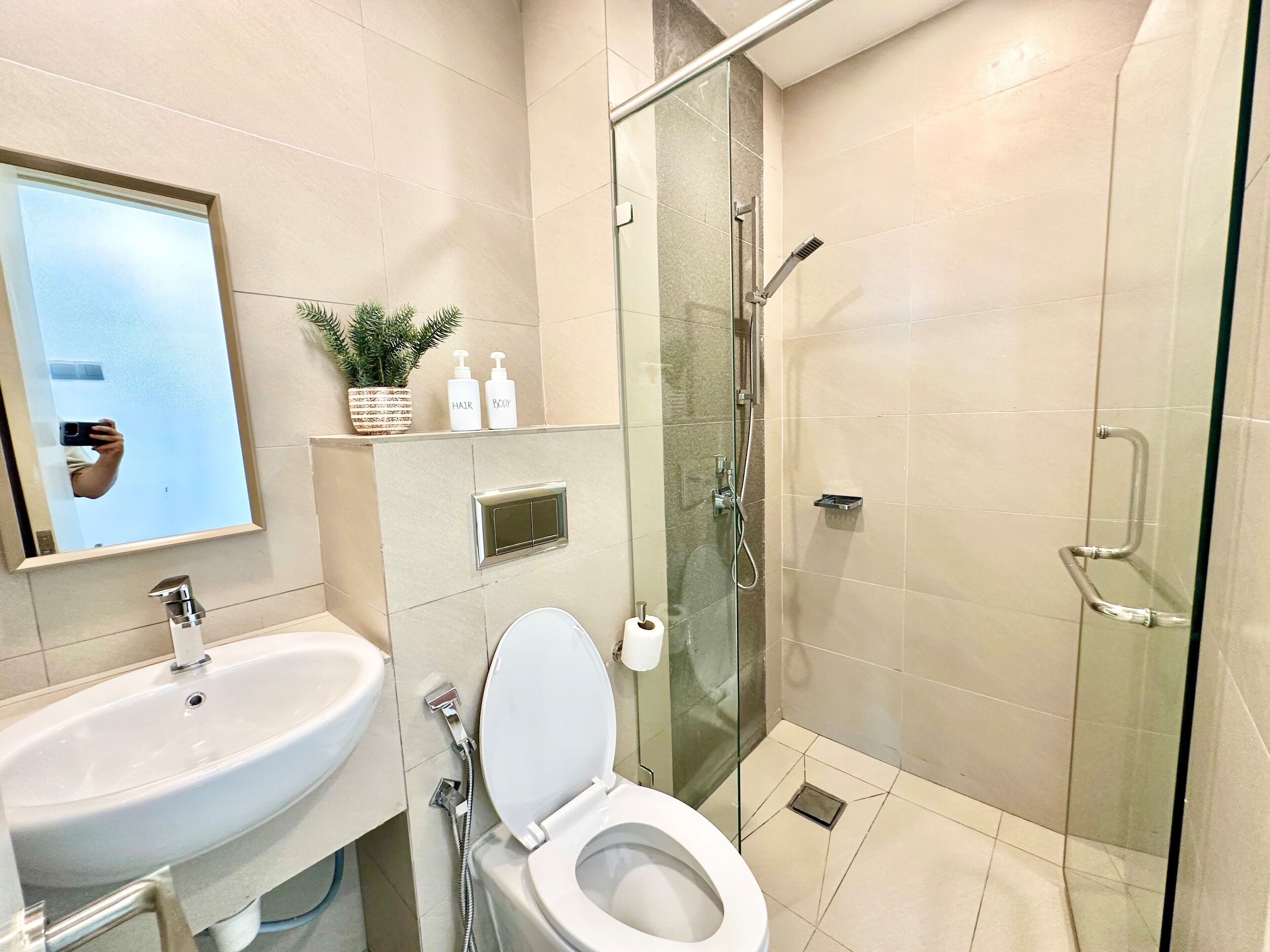 Un baño moderno con cabina de ducha de vidrio, un lavabo e inodoro.