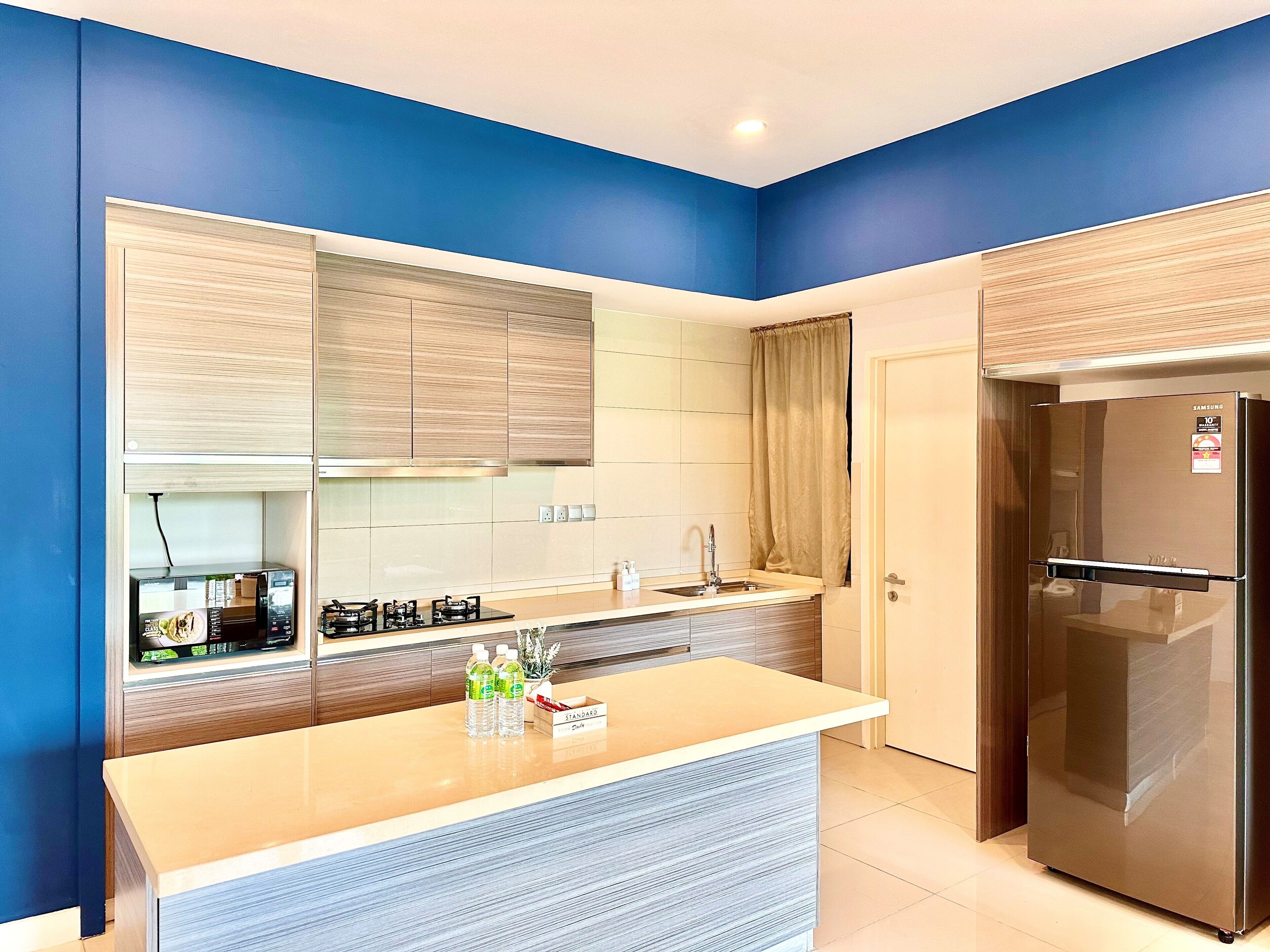Een moderne keuken met blauwe wanden, een roestvrijstalen koelkast en een ingebouwde gasfornuis.