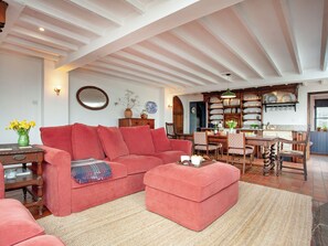 Ein gemütliches Wohnzimmer mit einem roten Sofa, einem Holzesstisch und einer Küchenzeile mit Regalen voller Geschirr.