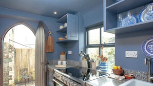 Una cocina con estufa, lavamanos y ventana con vistas a un jardín.