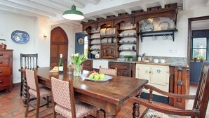 Comedor con mesa de madera, sillas y una araña.