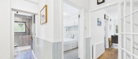 A hallway with a bed, a radiator, and a framed picture on the wall.