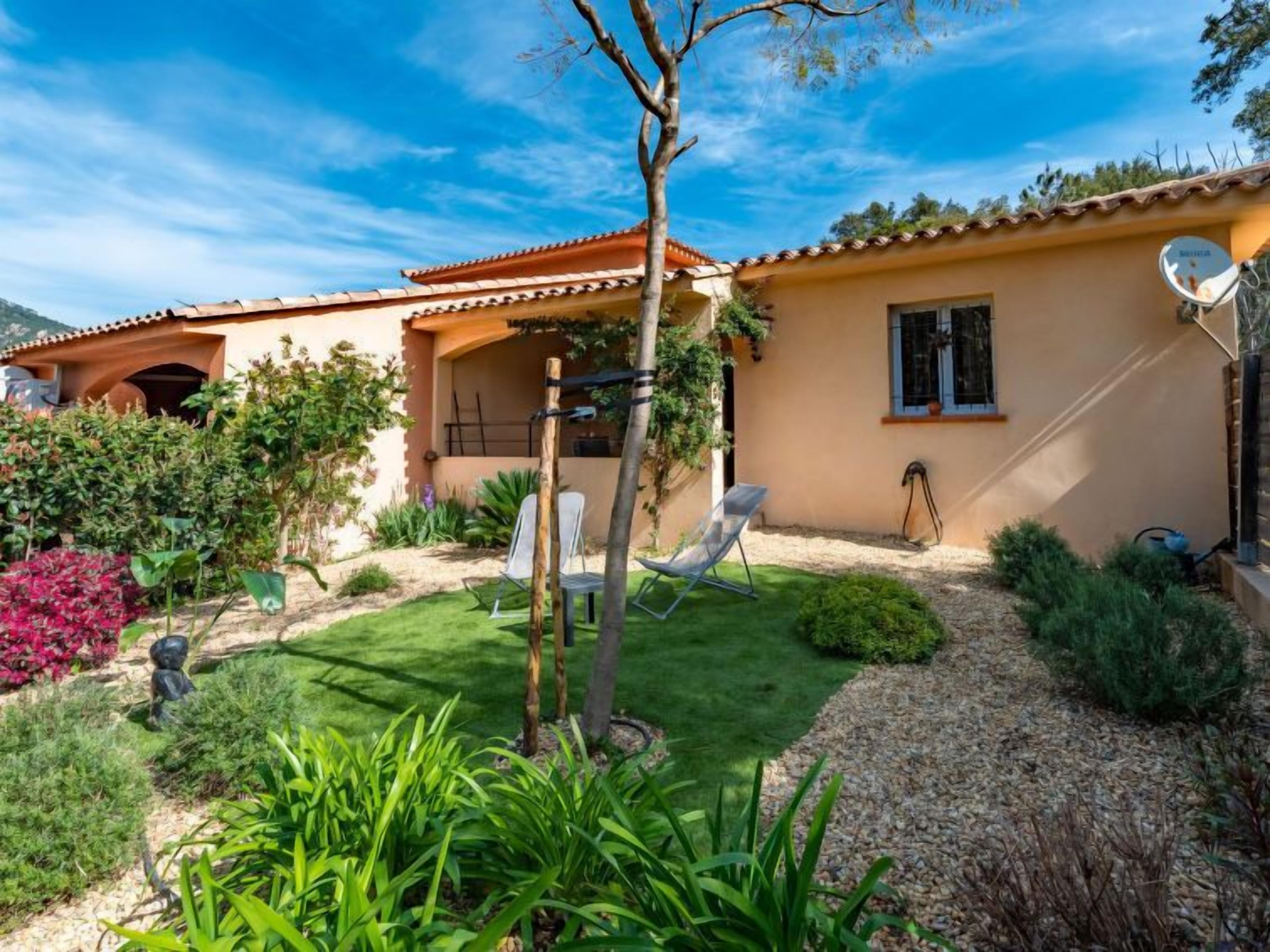 A house with a tiled roof, a garden with a lawn, and a satellite dish.