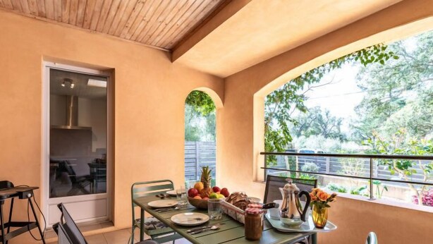 A dining area with a table set for four, a window with a view of greenery, and a door leading to another room. - Casa Brigitte by Interhome (Pinarellu)