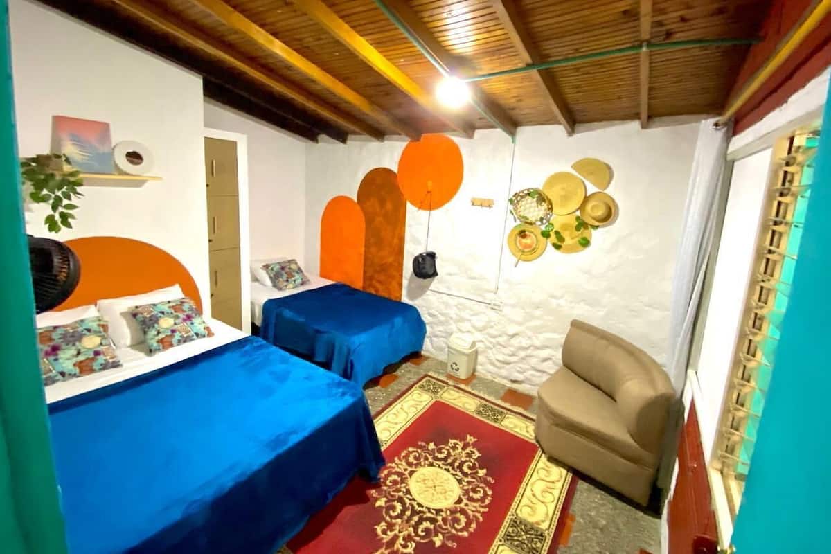 Quarto com duas camas, um sofá, uma parede decorada com pratos e teto de madeira.