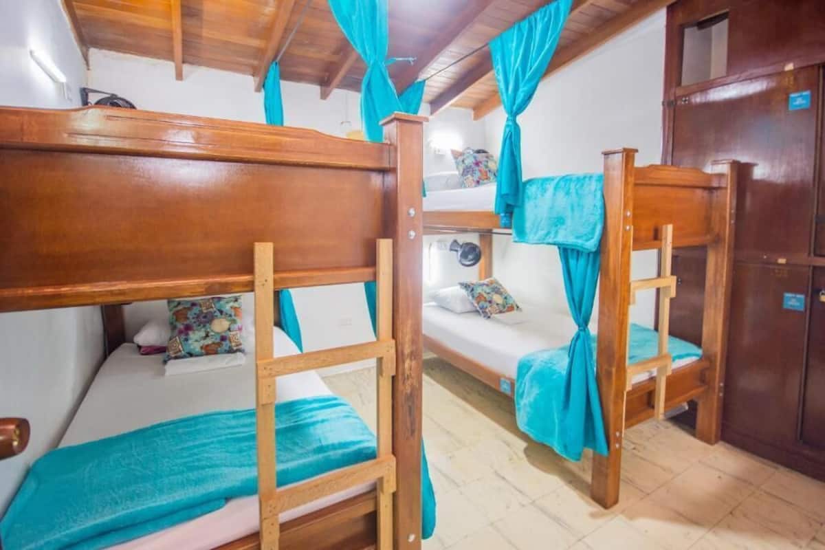 Quarto com beliches, cabeceiras de madeira e cortinas verde-água.
