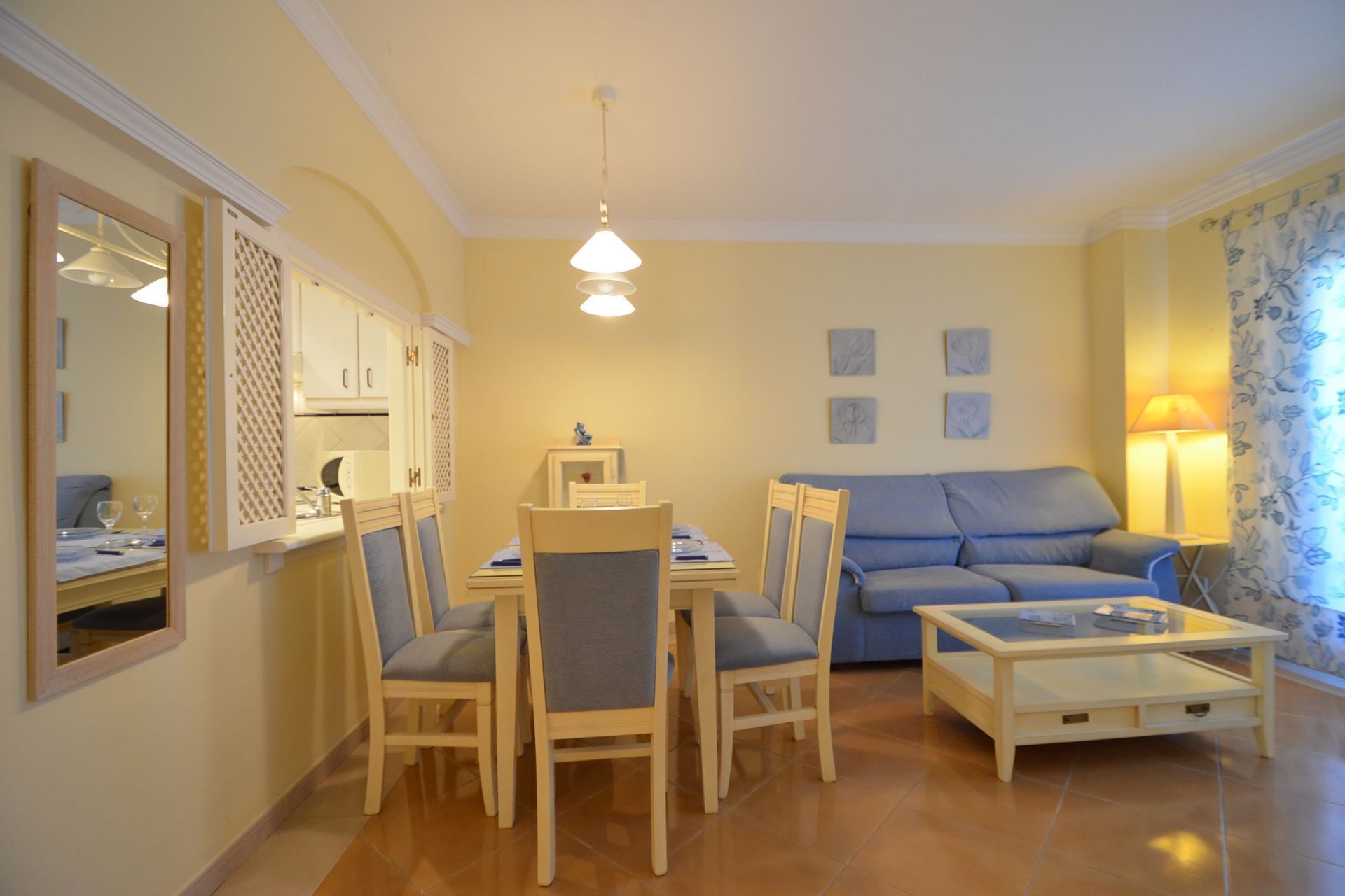 Un salon comprenant un canapé, des fauteuils, une table basse, une table à manger et un coin cuisine.
