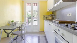 Cocina compacta con zona de comedor, que incluye una pequeña mesa, sillas y vistas a través de un ventanal.