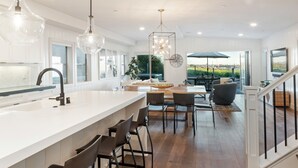 Een moderne keuken met een groot kookeiland, barstoelen en hanglampen.