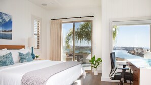 Een slaapkamer met een groot bed, een bureau en uitzicht op de oceaan.