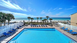 Un espace piscine avec des chaises bleues et vue sur la plage.