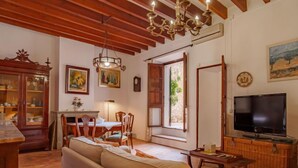 Una sala de estar acogedora con sofá, mesa de comedor, sillas, un televisor y un mueble de madera.