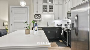 A modern kitchen with white cabinets, a stainless steel refrigerator, and a central island. - Reluxme| Luxury 1BR in Uptown w/ Resort Amenities (Charlotte)