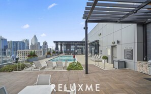 Área de piscina en la azotea con sillones, piscina y vista panorámica de la ciudad.