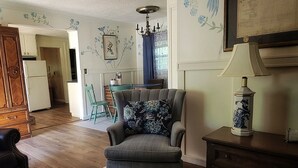 A cozy living room with a grey armchair, a wooden cabinet, and a blue patterned rug. - The "Frolic" (Pullman)
