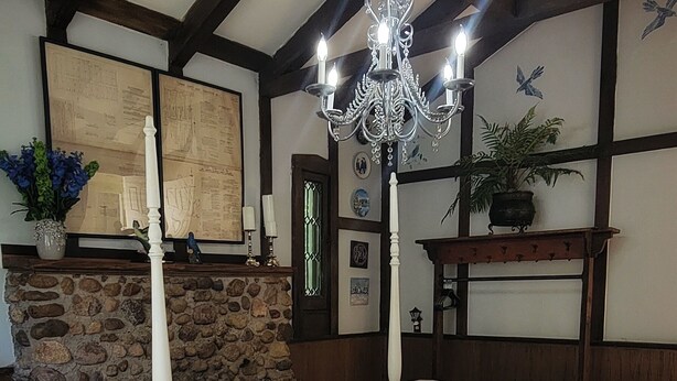 A bedroom with a stone fireplace, a chandelier, and a bed with a patterned bedspread. - The "Frolic" (Pullman)