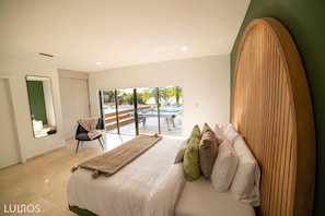 A bedroom with a bed, pillows, a chair, a mirror, and a view of an outdoor pool area. - Waterfront Resort • Room beach, Kayak, Pool & BBQ (Miami)
