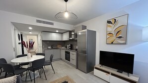A modern kitchen with a refrigerator, stove, and dining area. - Prestige view 411 by Avecoeur (Èze)