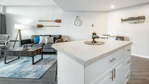A modern living room with a central island, a sofa, a coffee table, and a dining area with a table and chairs.