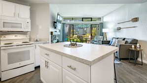A modern kitchen with white cabinetry, a built-in microwave, and a large island.