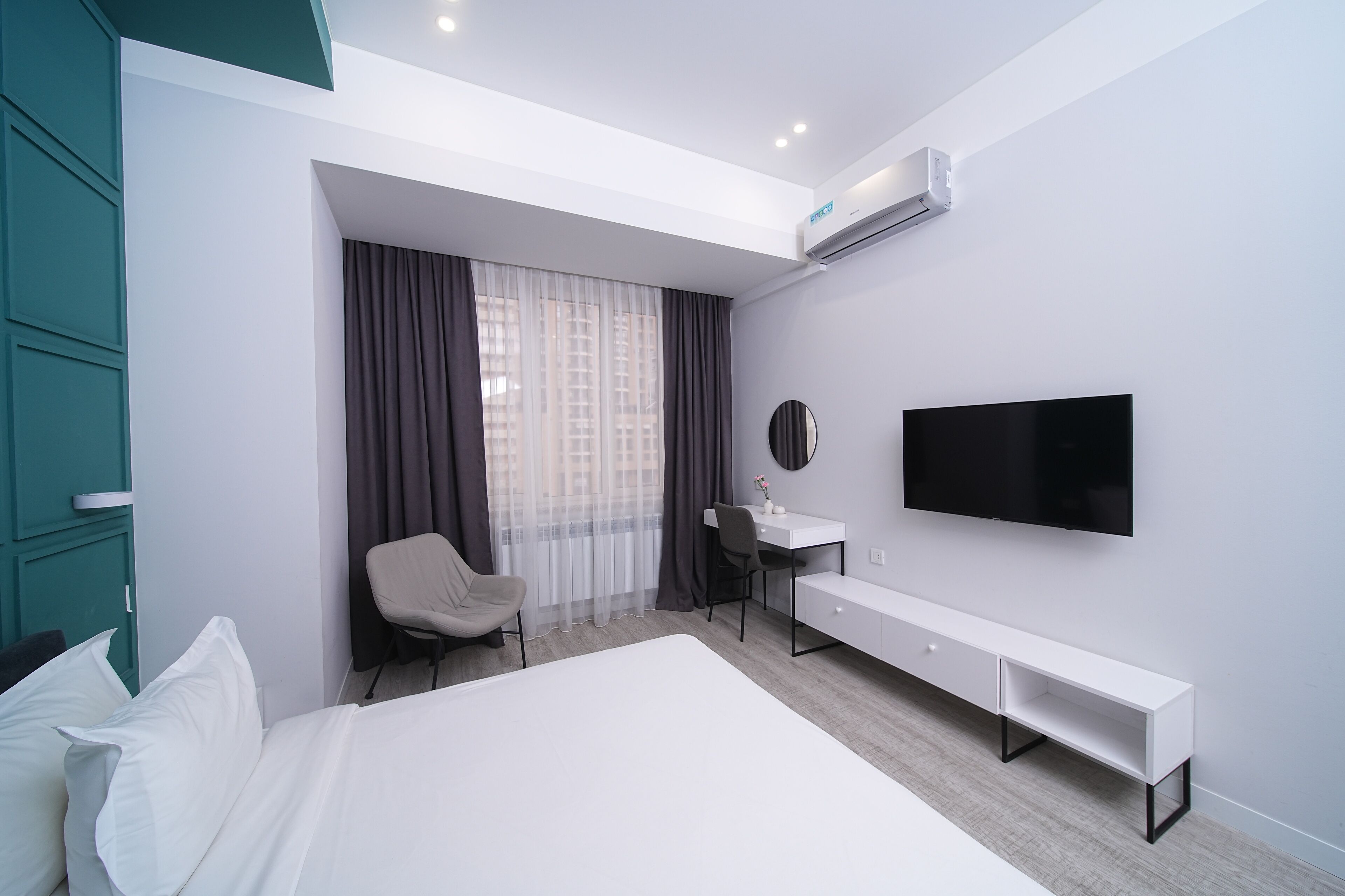 Une chambre d’hôtel moderne équipée d’un lit, d’un bureau, d’une chaise, d’une télévision et d’un appareil de climatisation.
