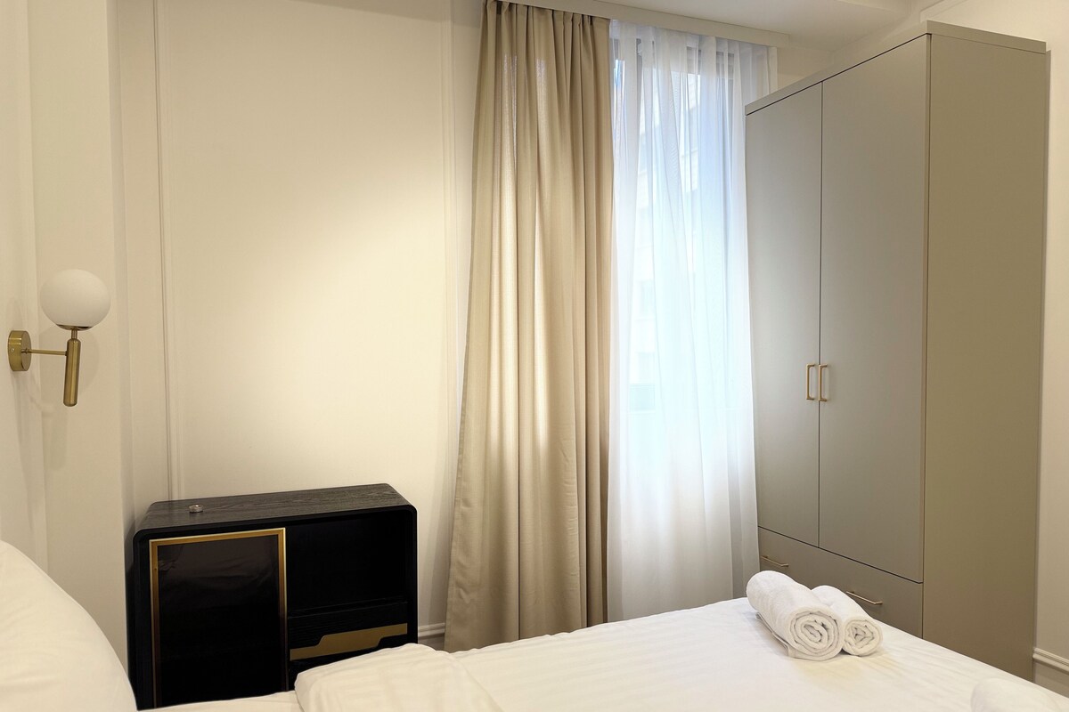 A hotel room with a bed, a nightstand, a wardrobe, and a window with curtains.