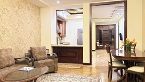 A living room with a sofa, coffee table, and a dining area with a table and chairs. - Sweet Home Apart-Hotel (Yerevan)