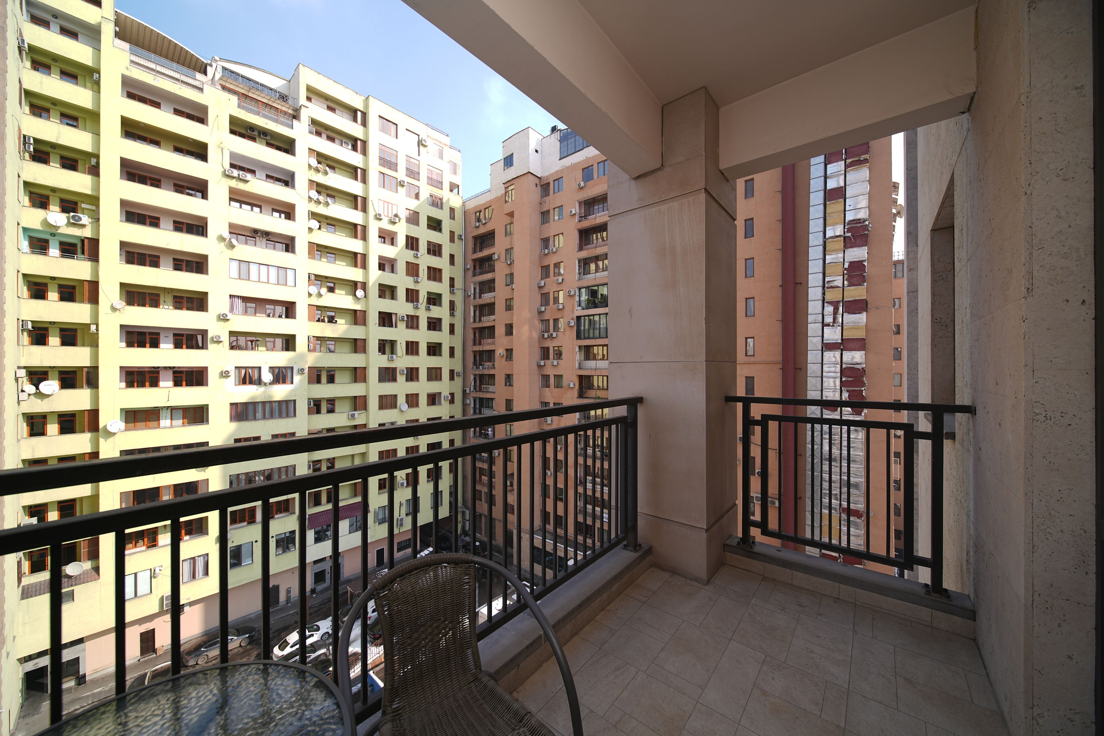 A balcony with a view of high-rise buildings, a chair, and a table.