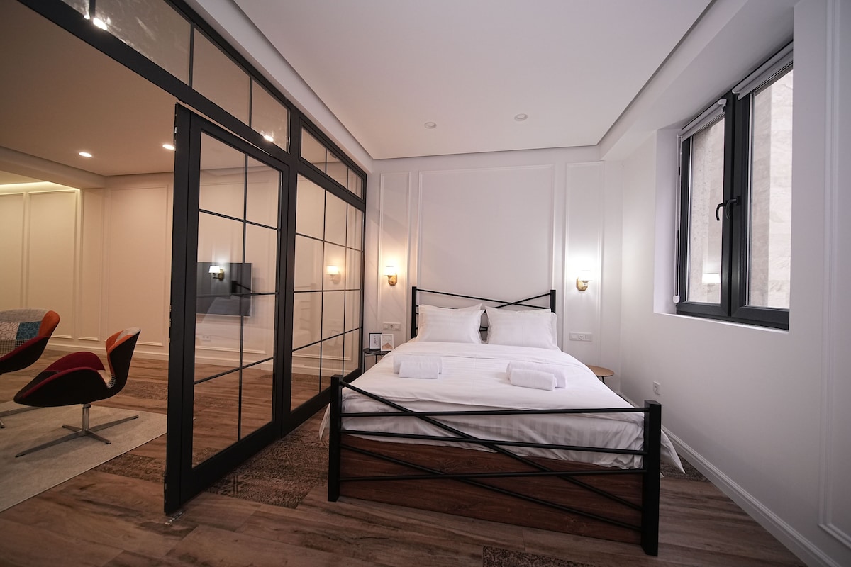 A modern bedroom with a large bed, a sliding glass door, and a window.