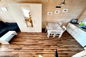 A compact, modern kitchen with a dining area, wooden flooring, and a built-in wardrobe.