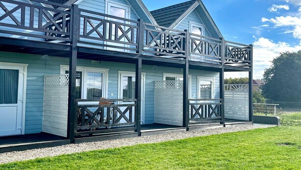 A two-story house with a balcony and a covered porch area. - Holiday Home in Pobierowo near Beach (Rewal)