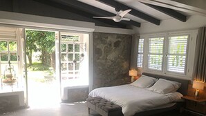 Um quarto com uma cama grande, um ventilador de teto e uma parede de pedra.