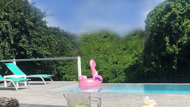 Uma mesa com bandeja para bebidas, ambiente à beira da piscina e um flutuador em formato de flamingo rosa.