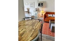 A dining area with a wooden table and chairs, a sofa, a lamp, and a wall with a sign. - 1BR Cottage Close to Beach! (Wildwood)