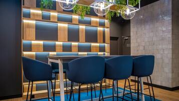 A modern interior with a wooden panel wall, a table with chairs, and hanging plants.