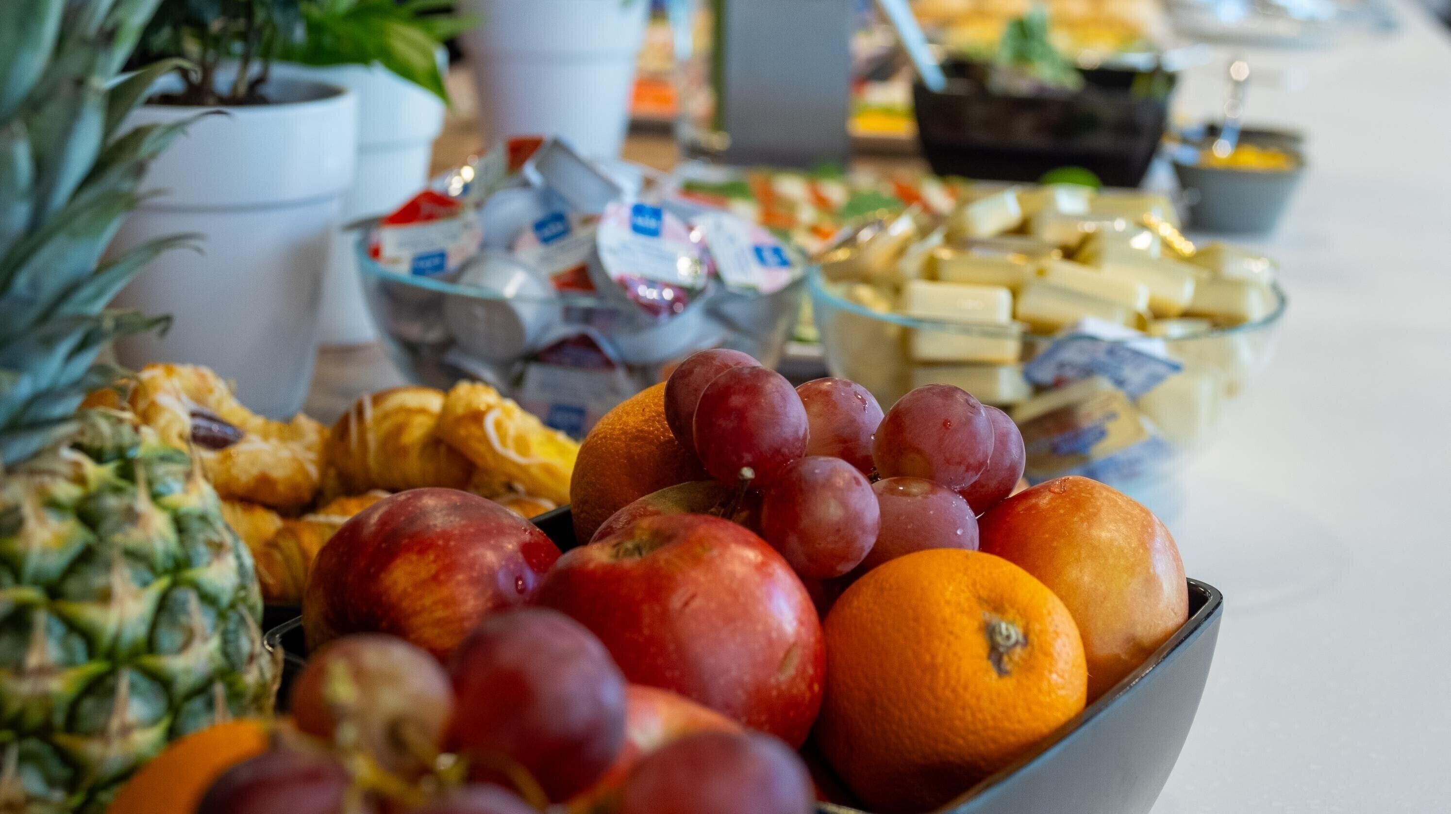 A table with a variety of fruits and pastries, including apples, oranges, and pastries.
