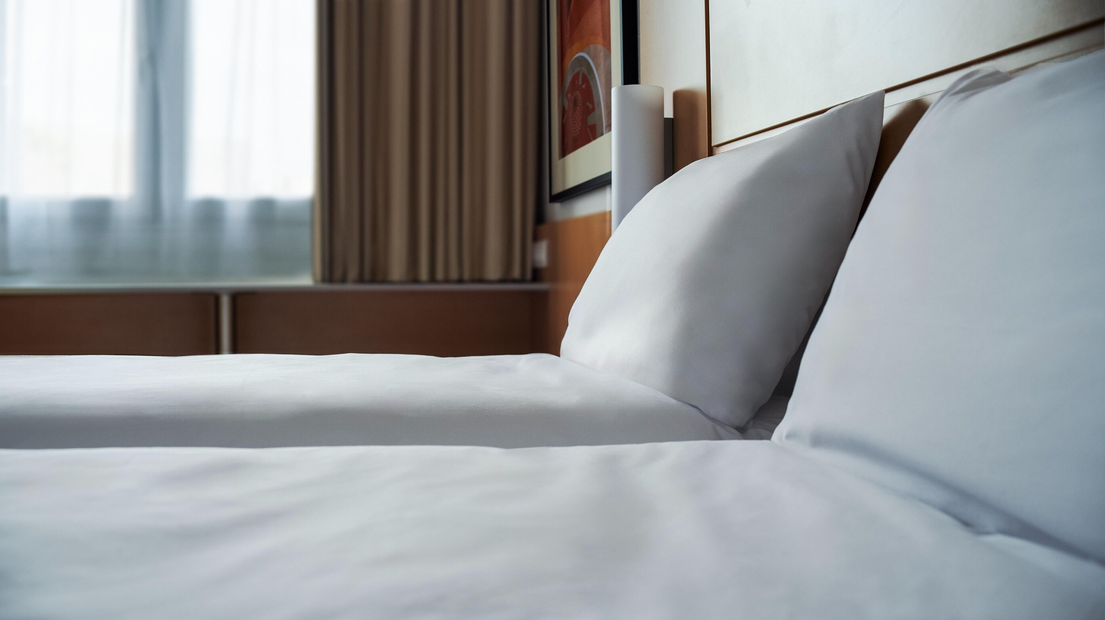 A neatly made bed with white linens in a hotel room.